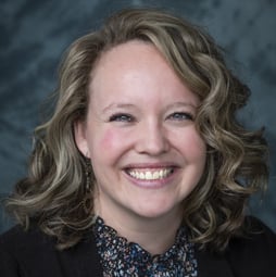 female on gray background, curly hair, smiling
